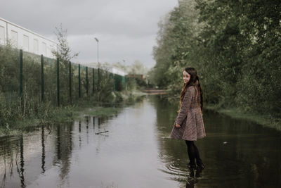 Woman walking by lake against sky