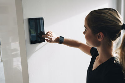 Teenage girl using tablet mounted on white wall at home