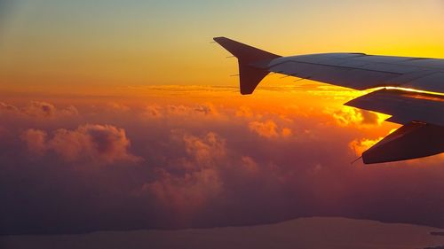 Airplane wing against sky during sunset