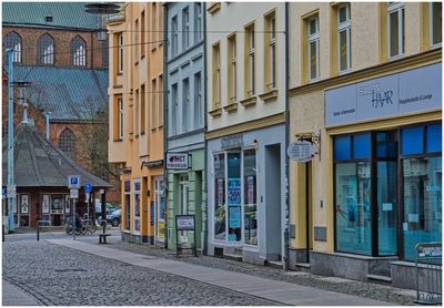 Empty road by buildings in city