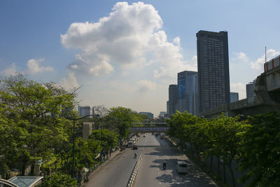 Road amidst trees and buildings against sky