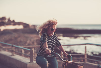 Midsection of woman standing by railing against sea