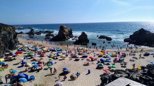 Group of people on rock by sea against sky