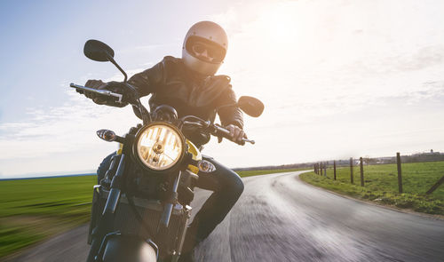 Man riding motorcycle on road against sky