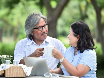 Mature couple having tea at table during picnic