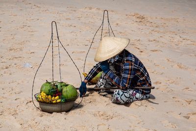 Male vendor sitting with fruits at beach