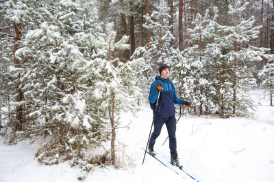 Skier with a backpack and hat with pompom with ski poles in his hands on background of a 