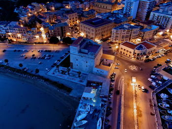 High angle view of illuminated street amidst buildings at night