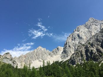 Low angle view of snowcapped mountains against blue sky