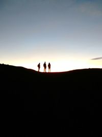 Silhouette people on mountain road against sky during sunset