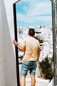 Young traveler looking through doorway over white spanish village