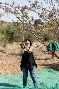 Portrait of a female farmer harvesting almonds by hand.