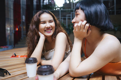 Smiling lesbian coupe drinking coffee while sitting at cafe