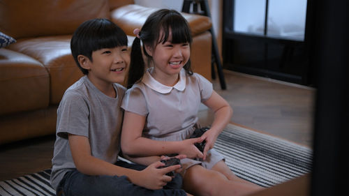 Siblings playing video game in living room at home