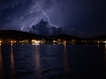 Panoramic view of lightning over sea against sky at night