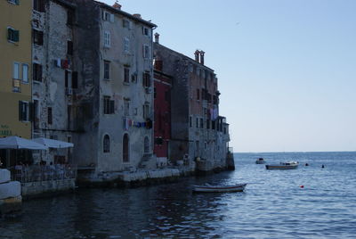 Boats in sea by buildings against clear sky