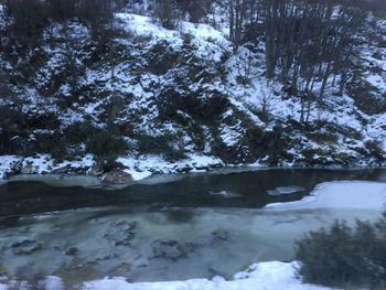 Stream flowing through snow covered forest