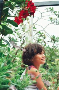 Side view of smiling cute girl looking away by flowering plants