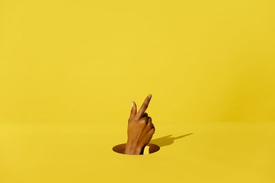Close-up of person hand on yellow background