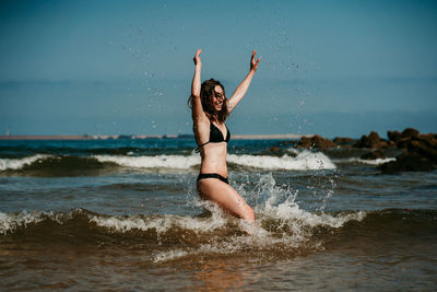 Full length of young woman at beach against sky