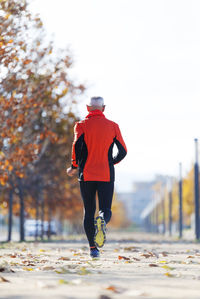 Rear view of senior man running on road during autumn