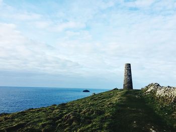 Lighthouse amidst sea and buildings against sky