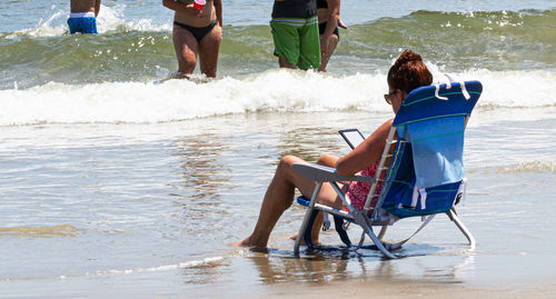Rear view of men sitting on beach