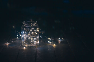 Close-up of illuminated glass jar on table