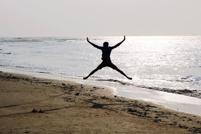 Silhouette man jumping on beach