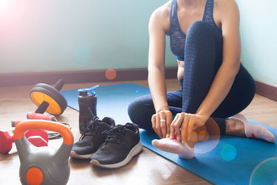 Low section of woman wearing socks while sitting on exercise mat