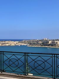 Scenic view of sea by buildings against clear blue sky