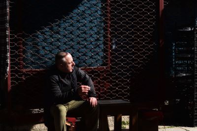 Young man looking away while sitting on floor