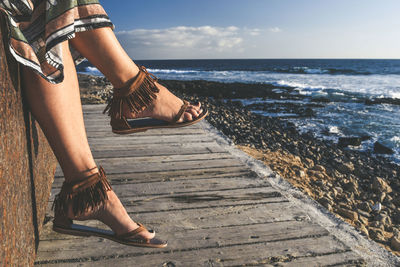 Low section of woman by sea against sky