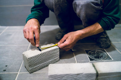 Low section of man marking on brick in bathroom