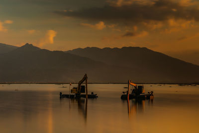 Silhouette boats in sea against sky during sunset