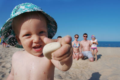 Portrait of happy boy standing on beach against clear sky