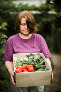 Young woman holding vegetables in container