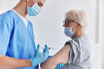 Doctor wearing mask vaccinating patient