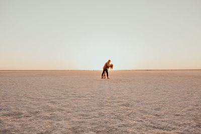 Rear view of woman walking on beach against clear sky