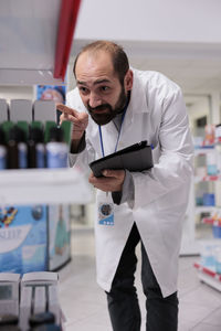 Portrait of young man using mobile phone while standing in laboratory