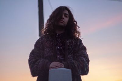 Low angle view of woman standing against sky during sunset