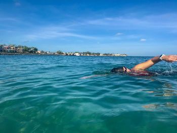 Woman swimming in sea against sky