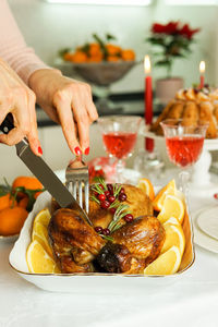 Women's hands with a red manicure cut a festive chicken. thanksgiving day , christmas and new year.