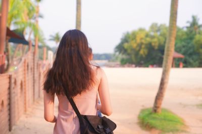 Rear view of woman standing against trees