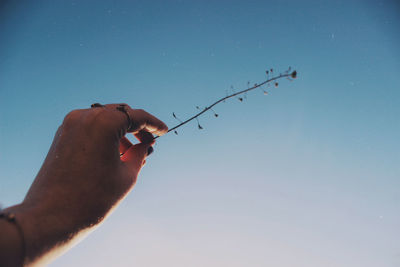 Low angle view of person hand against clear blue sky