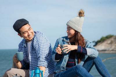 Happy young man using smart phone while sitting outdoors