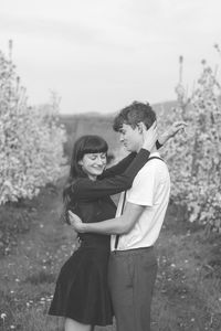 Young strong love between two young people walking under apple trees. black and white portrait.