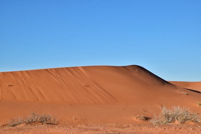 Scenic view of desert against clear blue sky