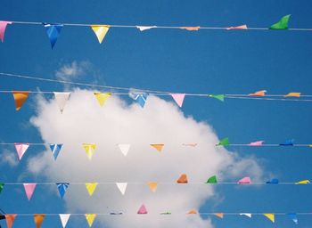 Low angle view of multi colored flags hanging against blue sky