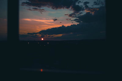 Silhouette trees against sky during sunset seen through window